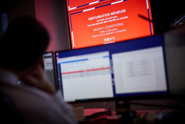 Airport staff monitor screens during a blizzard at Orly Airport, south of Paris on January 7, 2026. Around 100 flights were cancelled at Paris's Charles de Gaulle Airport because of snowfall and fierce cold, and a further 40 were cancelled at Orly Airport, France's transport minister said. (Photo by Kiran RIDLEY / AFP)