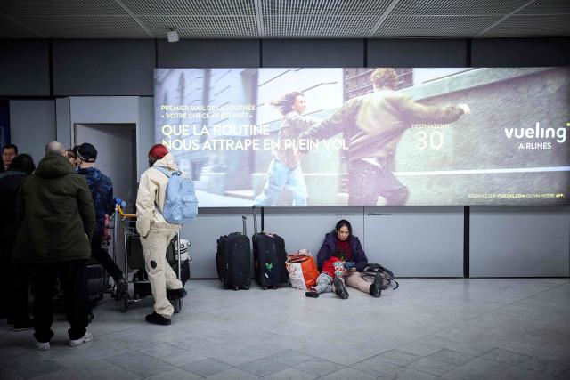 A woman and a child wait as several flights have been canceled during a blizzard at Orly Airport, south of Paris on January 7, 2026. Around 100 flights were cancelled at Paris's Charles de Gaulle Airport because of snowfall and fierce cold, and a further 40 were cancelled at Orly Airport, France's transport minister said. (Photo by Kiran RIDLEY / AFP)