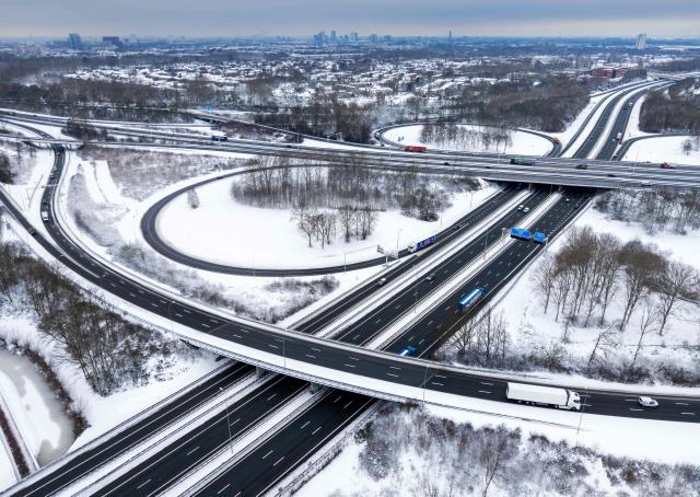A picture taken near Utrecht on January 7, 2026 shows vehicles traveling on a highway in a snowy landscape at the Lunetten interchange. (Photo by Robin van Lonkhuijsen / ANP / AFP) / Netherlands OUT