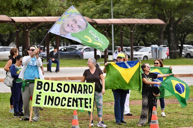 Supporters of former Brazilian President Jair Bolsonaro (2019-2022) protest against his arrest in front of the Federal Police headquarters in Brasilia on January 7, 2026. Bolsonaro was admitted to a hospital in Brasilia on January 7, after being transferred from prison, a day after he fell in his cell and hit his head, AFP journalists confirmed. (Photo by Evaristo Sa / AFP)
