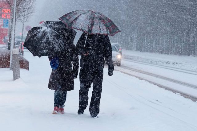 People use umbrellas to shelter from heavy snowfall in Aalborg, northern Denmark on January 7, 2026. Snow, ice and high winds brought transport chaos to swathes of Europe for a third day on January 7, 2026, with hundreds of flights cancelled and passengers stranded. (Photo by Henning Bagger / Ritzau Scanpix / AFP) / Denmark OUT
