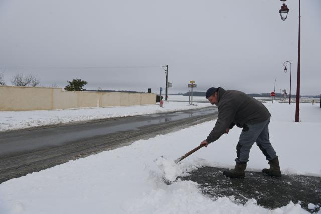 A resident clears snow from the sidewalk in front of his house after 7 centimeters of snow fell overnight, in Gohory, near Brou, central France, on January 7, 2026.  (Photo by JEAN-FRANCOIS MONIER / AFP)