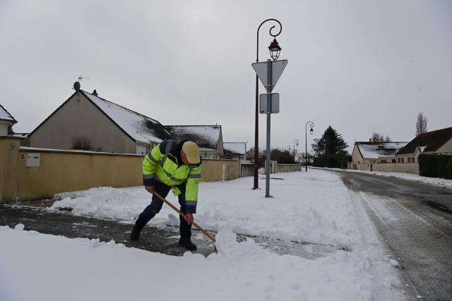 A resident clears snow from the sidewalk in front of his house after 7 centimeters of snow fell overnight, in Gohory, near Brou, central France, on January 7, 2026.  (Photo by JEAN-FRANCOIS MONIER / AFP)