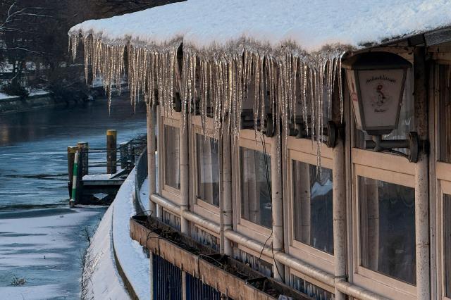 Icicles have formed from the roof of a bar overlooking the Landwehr canal in Berlin's Kreuzberg district on January 7, 2026 as freezing contitions continue in the German capital. Snow, ice and high winds brought transport chaos to swathes of Europe for a third day on January 7, 2026, with hundreds of flights cancelled and passengers stranded. (Photo by David GANNON / AFP)