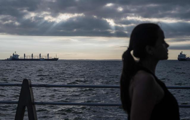 This view shows the silhouette of a woman as the crude oil ship Ithaca Patience (L), from Panama, is seen docked on Lake Maracaibo, Venezuela, on January 7, 2026. US Energy Secretary Chris Wright said in January 7, Washington will control sales of Venezuelan oil "indefinitely," a day after President Donald Trump announced Venezuela's interim leaders had agreed to US-managed marketing of 30-50 million barrels of crude. (Photo by Maryorin Mendez / AFP)