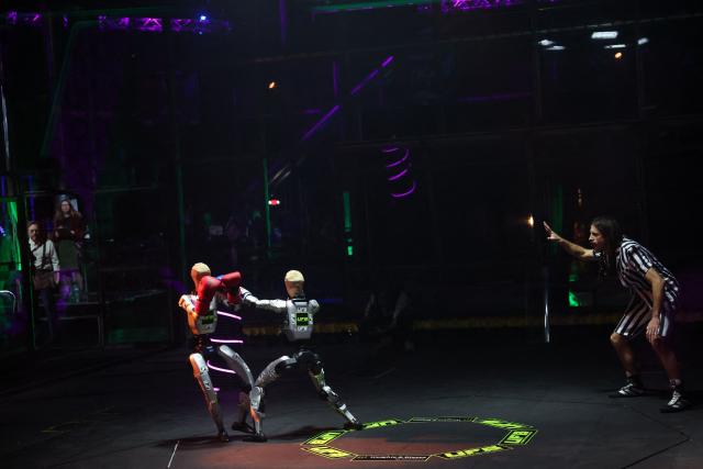 A referee signals a point on as robots wearing boxing gloves exchange punches during the Ultimate Fighting Bots (UFB) competition at the BattleBots Arena on the sidelines of the annual Consumer Electronics Show (CES) in Las Vegas, Nevada on January 6, 2026. (Photo by Patrick T. Fallon / AFP)
