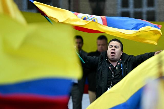 A man waves a Colombian flag during the March for Sovereignty and Democracy against US President Donald Trump's threats to Colombia's President Gustavo Petro at Bolivar Square in Bogota on January 7, 2026. On January 5, Colombian President Gustavo Petro said he was ready to "take up arms" in the face of threats from US counterpart Donald Trump, who over the weekend seized the leader of neighboring Venezuela in a military strike. (Photo by Luis ACOSTA / AFP)