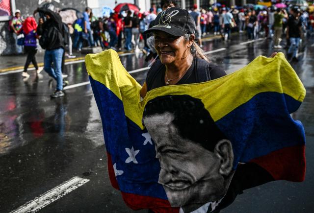 A demonstrator shows a Venezuelan flag depicting former Venezuelan President Hugo Chavez during a rally in support of ousted President Nicolas Maduro in Caracas on January 7, 2026. US Energy Secretary Chris Wright said in January 7, Washington will control sales of Venezuelan oil "indefinitely," a day after President Donald Trump announced Venezuela's interim leaders had agreed to US-managed marketing of 30-50 million barrels of crude. (Photo by Ronaldo SCHEMIDT / AFP)