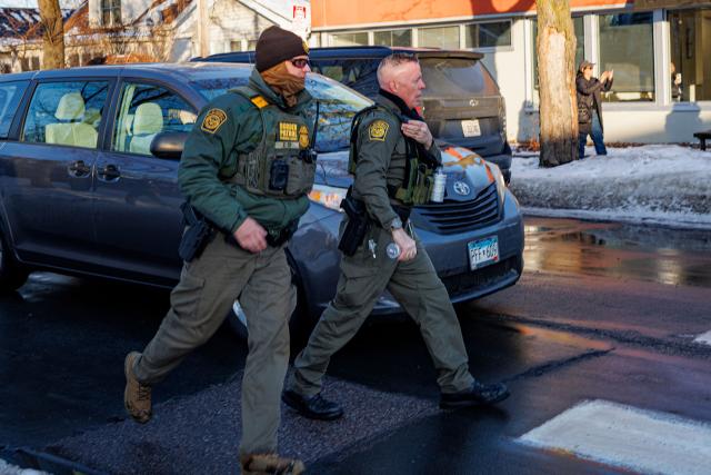 US Border Patrol Commander Gregory Bovino (R) walks near Roosevelt High School during dismissal time as federal immigration enforcement actions sparked protests in Minneapolis, Minnesota, on January 7, 2026. An immigration officer in Minneapolis shot dead a woman Wednesday, triggering outrage from local leaders even as US President Donald Trump claimed the officer acted in self-defense. Minneapolis Mayor Jacob Frey deemed the government's allegation that the woman was attacking federal agents "bullshit," and called on Immigration and Customs Enforcement (ICE) officers conducting a second day of mass raids to leave Minneapolis. (Photo by Kerem YUCEL / AFP)