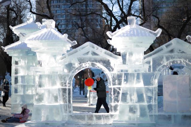 This picture taken on January 7, shows people visiting an ice sculpture at a park in Harbin, in northeastern China's Heilongjiang province. (Photo by AFP) / China OUT