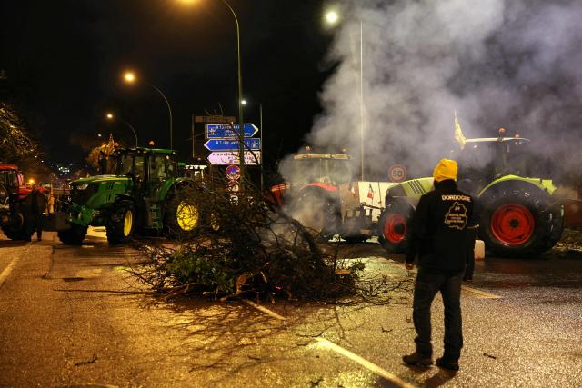 Branches are lit on fire across a road as people gather next to tractors during a demonstration of French agricultural union Coordination Rurale (CR) as part of a nationwide day of protests and actions called by several farmers unions to push the French government to block the Mercosur trade deal and protest against its handling of the nodular dermatitis (CND) epidemic, near the Porte d'Auteuil metro station in Paris on January 8, 2026. (Photo by Thomas SAMSON / AFP)