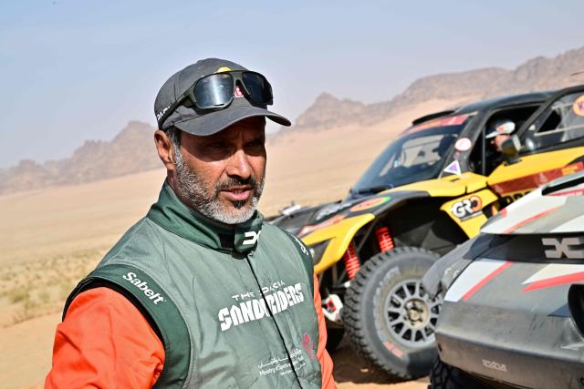 The Dacia Sandriders’s Qatari driver Nasser al-Attiyah and Belgian co?pilot Fabian Lurquin stand near his car at the end of the Stage 4, a Marathon stage, of the 48th edition of the Dakar Rally 2026, between Al-Ula and Al-Ula, Saudi Arabia, on January 7, 2026. (Photo by Giuseppe CACACE / AFP)