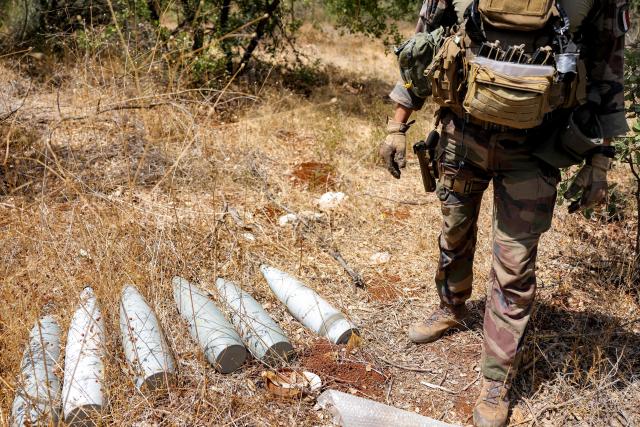 (FILES) A French peacekeeper of the United Nations Interim Force in Lebanon (UNIFIL) stands by munitions formerly used by Iran-backed Hezbollah at a position that was held by the group in the Khraibeh Valley in el-Meri in south Lebanon on August 27, 2025. Lebanon's army said on Januray 8, 2026, that it had completed the first phase of its plan to disarm Hezbollah in south Lebanon, while Israel called the efforts encouraging but "far from sufficient". Under heavy US pressure and amid fears of expanded Israeli strikes, Lebanon has committed to disarming the Iran-backed militant group, which was badly weakened after more than a year of hostilities including two months of all-out war that ended with a November 2024 ceasefire. (Photo by ANWAR AMRO / AFP)