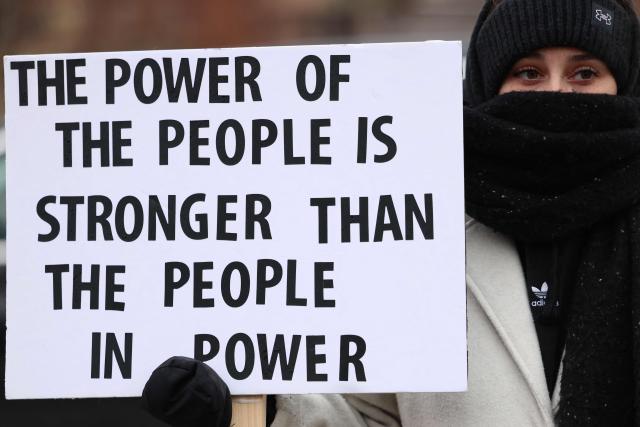 A woman holds a sign near the street where 37-year-old Renee Nicole Good was shot and killed at point blank range on January 7 by a US Immigration and Customs Enforcement (ICE) agent as she apparently tried to drive away from agents who were crowding around her car, in Minneapolis, Minnesota, on January 8, 2026. A US Immigration and Customs Enforcement (ICE) agent shot and killed an American woman on the streets of Minneapolis January 7, leading to huge protests and outrage from local leaders who rejected White House claims she was a domestic terrorist. (Photo by CHARLY TRIBALLEAU / AFP)
