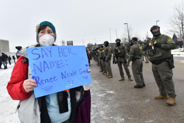 A protestor holds a sign as federal agents stand guard as protestors gather outside the Bishop Henry Whipple Federal Building in Saint Paul, Minnesota, on January 8, 2026. A US Immigration and Customs Enforcement (ICE) agent shot and killed an American woman on the streets of Minneapolis January 7, leading to huge protests and outrage from local leaders who rejected White House claims she was a domestic terrorist. The woman, identified in local media as 37-year-old Renee Nicole Good, was hit at point blank range as she apparently tried to drive away from agents who were crowding around her car, which they said was blocking their way. (Photo by Octavio JONES / AFP)