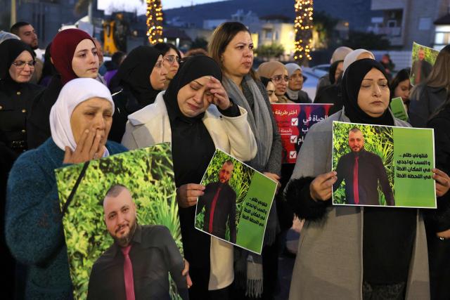 Israeli-Arab demonstrators hold pictures of victims of violence during a protest organised by a left leaning NGO, Standing Together, in response to a sharp rise in murders within Israel's Arab society, demanding that the government present a solution to curb the violence in Turan on January 8, 2026. (Photo by JACK GUEZ / AFP)