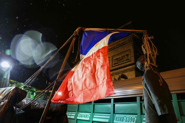 This photograph shows a dummy hanged with a a French flag displayed on a tractor in front of the Arc de Triomphe monument during a demonstration of the Coordination Rurale (CR) farmers union as part of a nationwide day of protests and actions called by several farmers unions to push the French government to block the Mercosur trade deal and protest against its handling of the nodular dermatitis (CND) epidemic, in Paris on January 8, 2026. (Photo by Alain JOCARD / AFP)
