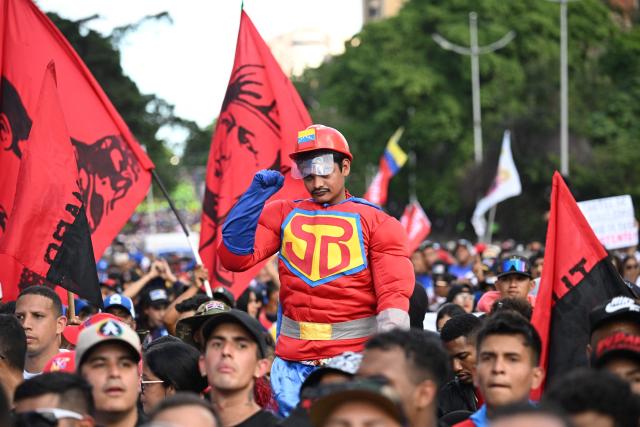 A demonstrator dressed as the caped superhero named "Super-Bigote" (Super-Mustache) attends a Chavismo youth march in Caracas on January 8, 2026, to demand their release after they were snatched and taken to New York on January 3 to face trial on drug and weapons charges. Venezuela on January 8 announced the release of a "large number" of prisoners, some of them foreigners, in an apparent concession to the United States after its ouster of ruler Nicolas Maduro. (Photo by Federico PARRA / AFP)