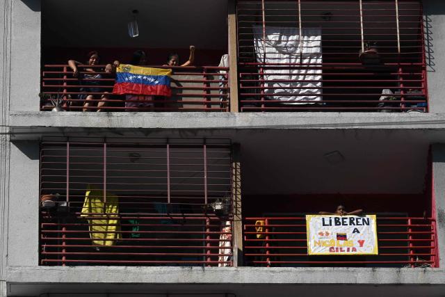 Locals look out from their balconies during a Chavismo youth march in Caracas on January 8, 2026, to demand the release of deposed Venezuelan president Nicolas Maduro and his wife Cilia Flores, snatched and taken to New York on January 3 to face trial on drug and weapons charges. Venezuela on January 8 announced the release of a "large number" of prisoners, some of them foreigners, in an apparent concession to the United States after its ouster of ruler Nicolas Maduro. (Photo by Federico PARRA / AFP)