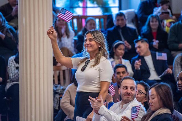 New citizens wave US flags as the judge calls out the countries they came from at Faneuil Hall in Boston, Massachusetts on January 8, 2026. (Photo by Joseph Prezioso / AFP)