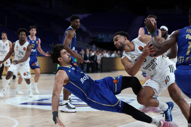 Maccabi's Brazilian center #03 Marcio Santos falls as he defends Real Madrid's Canadian forward #00 Trey Lyles during the Euroleague basketball match between Real Madrid and Maccabi Tel Aviv at Movistar Arena in Madrid on January 8, 2026. Real Madrid plays a EuroLeague basketball game against Maccabi Rapyd Tel Aviv behind closed doors over security concerns, the latest disruption to Spanish sport linked to Israeli participation. (Photo by Thomas COEX / AFP)