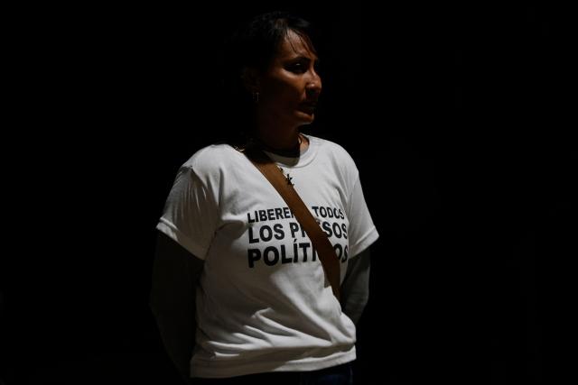 A woman wearing a t-shirt that reads in Spanish "Release all political prisoners" is pictured outside of El Rodeo jail in Caracas on January 8, 2026. Venezuelan authorities are releasing a "large number" of prisoners, some of them foreigners, five days after US forces ousted authoritarian leader Nicolas Maduro, parliament speaker Jorge Rodriguez said o January 8. (Photo by Pedro MATTEY / AFP)