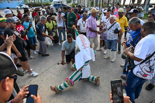 An Ireme (C), the masked dancer of the male religious secret society known as Abakua (or Nanigo), performs during Abakua Day celebrations in the Regla neighborhood of Havana, Cuba on January 8, 2026. The Afro-Cuban fraternity Abakua, a secret society that only accepts heterosexual men, marks 190 years since its creation in Cuba. The society was founded in the Havana municipality of Regla during Spanish colonial times by African slaves brought to the island from Nigeria. (Photo by YAMIL LAGE / AFP)