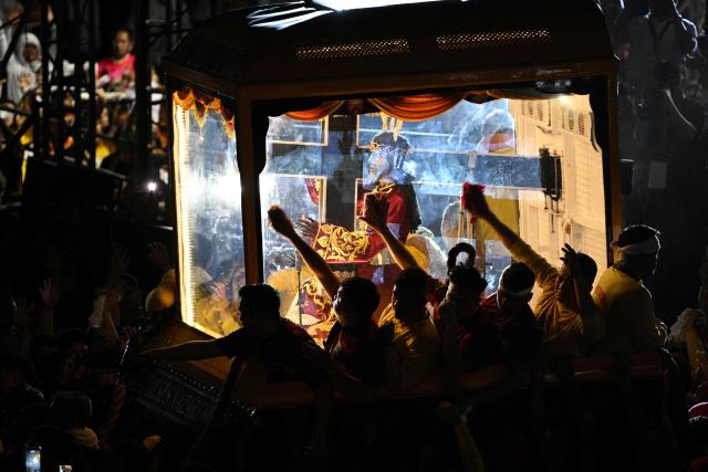 Philippine catholic devotees using towels wipe the glass of the carriage carrying the image of Jesus Nazarene during the annual religious procession in Manila on January 9, 2026. (Photo by TED ALJIBE / AFP)