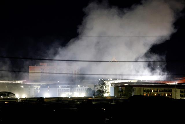 (FILES) Smoke rises over buildings following an explosion in the KK Park compound in eastern Myanmar, as pictured from Mae Sot District in Thailand's Tak Province on October 24, 2025. China is moving against the cyberscam tycoons making fortunes in Southeast Asia, driven by mounting public pressure and Beijing's desire to keep control of judicial processes, analysts say. 
In 2025, a series of crackdowns largely driven by Beijing -- which wields significant economic and diplomatic influence in the region -- saw thousands of workers released from scam centres in Myanmar and Cambodia and repatriated to their home countries, many of them to China.
Now Beijing has turned its focus to the bosses at the apex of the criminal pyramids, netting its biggest player so far with the arrest and extradition of Chen Zhi from Cambodia in January 2026. (Photo by Sarot Meksophawannakul / THAI NEWS PIX / AFP) / TO GO WITH Cambodia-China-cybercrime-diplomacy, FOCUS by Sally JENSEN