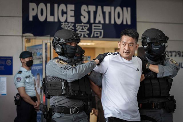 (FILES) Chinese businessman She Zhijiang (2nd R) is escorted by Royal Thai Police out of the Suvarnabhumi Airport Police Station in Bangkok on November 12, 2025, before being extradited to China. China is moving against the cyberscam tycoons making fortunes in Southeast Asia, driven by mounting public pressure and Beijing's desire to keep control of judicial processes, analysts say. 
In 2025, a series of crackdowns largely driven by Beijing -- which wields significant economic and diplomatic influence in the region -- saw thousands of workers released from scam centres in Myanmar and Cambodia and repatriated to their home countries, many of them to China.
Now Beijing has turned its focus to the bosses at the apex of the criminal pyramids, netting its biggest player so far with the arrest and extradition of Chen Zhi from Cambodia in January 2026. (Photo by Chanakarn Laosarakham / AFP) / TO GO WITH Cambodia-China-cybercrime-diplomacy, FOCUS by Sally JENSEN
