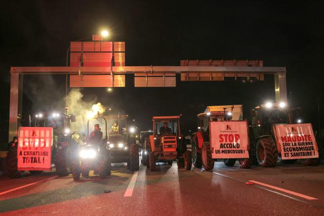 Tractors are used to block traffic as members of the Confederation Paysanne farmers union take part in an action aimed at slowing down traffic on Paris' ring road by Porte de Montreuil, to push the French government to block the Mercosur trade deal and protest against its handling of the nodular dermatitis (CND) epidemic, in Paris on January 9, 2026. (Photo by Thomas SAMSON / AFP)