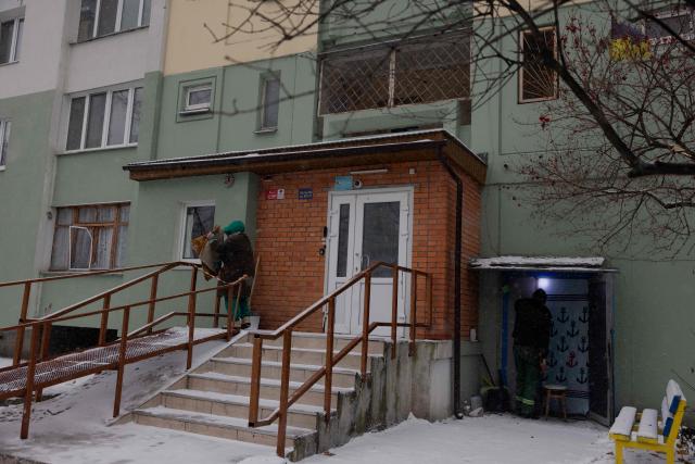 A woman shakes out a rug near a damaged residential building following a Russian attack in Kyiv early on January 9, 2026, amid the Russian invasion of Ukraine. Russia launched a massive attack on Ukraine's capital, setting apartment blocks alight and killing at least four people, Kyiv's police said on January 9, 2026 after Moscow rejected the latest post-war peacekeeping plan. (Photo by Tetiana DZHAFAROVA / AFP)