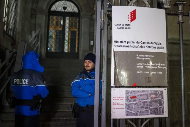 Police officers stand guard at the entrance of the Office of the public prosecutor of the Canton of Valais, prior to the hearing of French owners of Le Constellation bar in Sion on January 9, 2026. The French couple, facing charges of manslaughter by negligence, bodily harm by negligence and arson by negligence, have been called in for questioning after 40 people, most of them teenagers, were killed, while 116 were injured in a fire that ripped through a bar in the luxury Alpine ski resort of Crans-Montana on New Year's Eve. (Photo by Fabrice COFFRINI / AFP)
