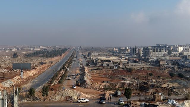 An aerial photograph shows buses as they enter from the Lairamoun roundabout towards the Sheikh Maqsud neighbourhood, to evacuate the US-backed Kurdish-led Syrian Democratic Forces (SDF) forces fighters from two districts of the city of Aleppo, northern Syria, on January 9, 2026. Kurdish fighters encircled by the Syrian army are to be sent to the Kurdish region of northeastern Syria, the Syrian authorities said January 9, 2026. Syria's defence ministry earlier announced a ceasefire in the city after several days of clashes and granted the Kurdish fighters a deadline to leave two districts they control. (Photo by Bakr ALKASEM / AFP)