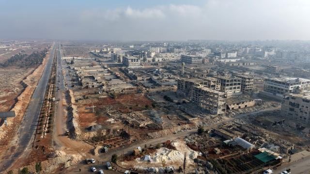 An aerial photograph shows buses as they enter from the Lairamoun roundabout towards the Sheikh Maqsud neighbourhood, to evacuate the US-backed Kurdish-led Syrian Democratic Forces (SDF) forces fighters from two districts of the city of Aleppo, northern Syria, on January 9, 2026. Kurdish fighters encircled by the Syrian army are to be sent to the Kurdish region of northeastern Syria, the Syrian authorities said January 9, 2026. Syria's defence ministry earlier announced a ceasefire in the city after several days of clashes and granted the Kurdish fighters a deadline to leave two districts they control. (Photo by Bakr ALKASEM / AFP)
