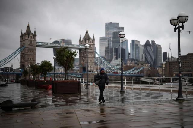 A pedestrian walks past Tower Bridge (behind) along the River Thames on a cold, grey day in central London on January 9, 2026. The United Kingdom, France and Germany shivered through severe winter weather on January 9, with tens of thousands of homes suffering the cold snap without power. (Photo by Henry NICHOLLS / AFP)
