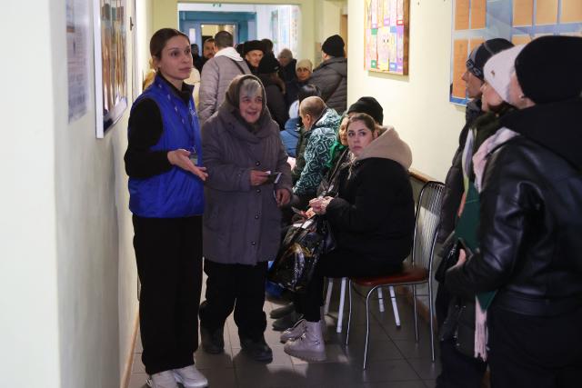 An employee (L) talks to residents who were forcibly evacuated from the villages of Kushuhum and Yuliivka in the Zaporizhzhia region at a transit centre in Zaporizhzhia on January 9, 2026, amid the Russian invasion of Ukraine. (Photo by Darya NAZAROVA / AFP)