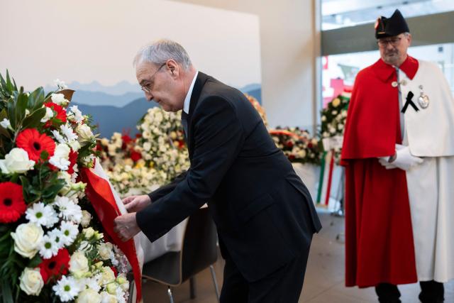 Switzerland's President Guy Parmelin arranges a floral wreath ahead of a tribute ceremony for the victims of the deadly fire that ripped through the bar Le Constellation in Crans-Montana on New Year's Eve, in Martigny on January 9, 2026. All of Switzerland will mark a national day of mourning on January 9 for the dozens of mostly teenagers killed when fire ravaged a ski resort bar crammed with New Year revellers. Just over a week after the tragedy at the Le Constellation bar in Crans-Montana, which left 40 dead and 116 injured, the wealthy Alpine nation will come to a standstill for a minute of silence at 2:00 pm (1300 GMT). (Photo by MICHAEL BUHOLZER / POOL / AFP)