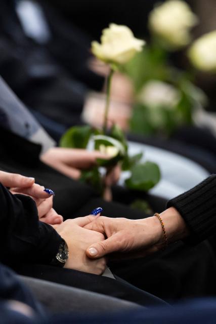 Attendees hold white roses during the tribute ceremony for the victims of the deadly fire that ripped through the bar Le Constellation in Crans-Montana on New Year's Eve, in Martigny, on January 9, 2026. All of Switzerland will mark a national day of mourning on January 9 for the dozens of mostly teenagers killed when fire ravaged a ski resort bar crammed with New Year revellers. Just over a week after the tragedy at the Le Constellation bar in Crans-Montana, which left 40 dead and 116 injured, the wealthy Alpine nation will come to a standstill for a minute of silence at 2:00 pm (1300 GMT). (Photo by MICHAEL BUHOLZER / POOL / AFP)