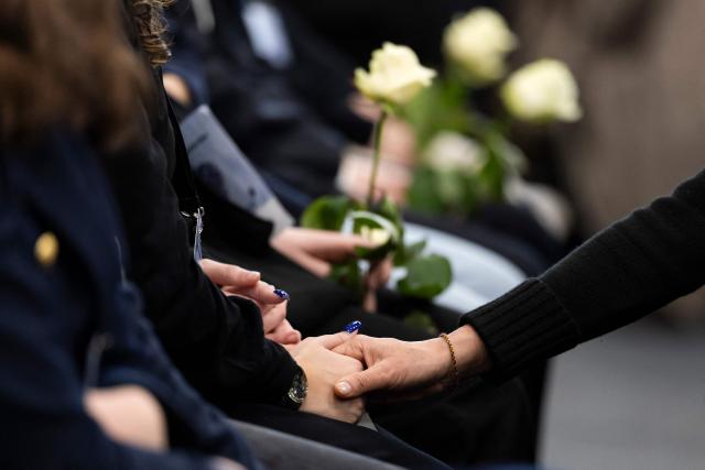 Attendees hold white roses during the tribute ceremony for the victims of the deadly fire that ripped through the bar Le Constellation in Crans-Montana on New Year's Eve, in Martigny, on January 9, 2026. All of Switzerland will mark a national day of mourning on January 9 for the dozens of mostly teenagers killed when fire ravaged a ski resort bar crammed with New Year revellers. Just over a week after the tragedy at the Le Constellation bar in Crans-Montana, which left 40 dead and 116 injured, the wealthy Alpine nation will come to a standstill for a minute of silence at 2:00 pm (1300 GMT). (Photo by MICHAEL BUHOLZER / POOL / AFP)