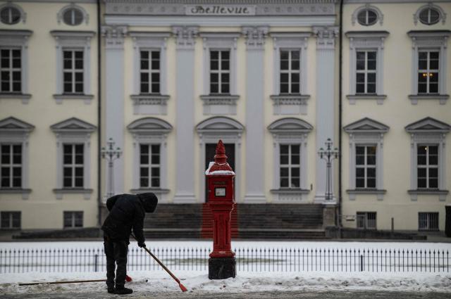 A worker clears ice and snow in front of the Bellevue palace in Berlin on January 9, 2026. Storm Elli has arrived in northern Germany with heavy winds and snow. (Photo by John MACDOUGALL / AFP)