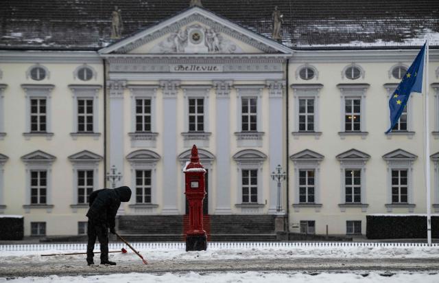 A worker clears ice and snow in front of the Bellevue presidential palace in Berlin on January 9, 2026. Storm Elli has arrived in northern Germany with heavy winds and snow. (Photo by John MACDOUGALL / AFP)
