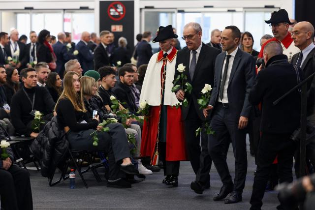 Switzerland's President Guy Parmelin (C-L) and State councillor and president of the Council of State of the Canton of Valais Mathias Reynard (C-R) hold white roses at the end of a tribute ceremony for the victims of the deadly fire that ripped through the bar Le Constellation in Crans-Montana on New Year's Eve, in Martigny, on January 9, 2026. All of Switzerland will mark a national day of mourning on January 9 for the dozens of mostly teenagers killed when fire ravaged a ski resort bar crammed with New Year revellers. Just over a week after the tragedy at the Le Constellation bar in Crans-Montana, which left 40 dead and 116 injured, the wealthy Alpine nation will come to a standstill for a minute of silence at 2:00 pm (1300 GMT). (Photo by Pierre Albouy / POOL / AFP)