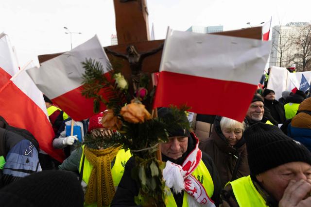 A participant holds a crucifix decorated with Polish national flags, during a protest against the EU-Mercosur agreement in Warsaw, Poland on January 9, 2026. The EU gave on January 9, 2025 a long-delayed go, ahead to a huge trade deal with South American bloc Mercosur championed by business groups but loathed by many European farmers. (Photo by Wojtek RADWANSKI / AFP)