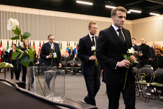 France's President Emmanuel Macron (R), Luxembourg's former Grand Duke Henri (C) walk with white roses after the tribute ceremony for the victims of the deadly fire that ripped through the bar Le Constellation in Crans-Montana on New Year's Eve, in Martigny, on January 9, 2026. All of Switzerland will mark a national day of mourning on January 9 for the dozens of mostly teenagers killed when fire ravaged a ski resort bar crammed with New Year revellers. Just over a week after the tragedy at the Le Constellation bar in Crans-Montana, which left 40 dead and 116 injured, the wealthy Alpine nation will come to a standstill for a minute of silence at 2:00 pm (1300 GMT). (Photo by MICHAEL BUHOLZER / POOL / AFP)