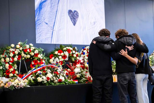 Attendees observe a moment in front of wreaths during the tribute ceremony for the victims of the deadly fire that ripped through the bar Le Constellation in Crans-Montana on New Year's Eve, in Martigny, on January 9, 2026. All of Switzerland will mark a national day of mourning on January 9 for the dozens of mostly teenagers killed when fire ravaged a ski resort bar crammed with New Year revellers. Just over a week after the tragedy at the Le Constellation bar in Crans-Montana, which left 40 dead and 116 injured, the wealthy Alpine nation will come to a standstill for a minute of silence at 2:00 pm (1300 GMT). (Photo by LAURENT GILLIERON / POOL / AFP)