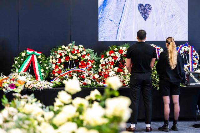 Relatives of victims observe a moment of silence in front of floral wreaths after a tribute ceremony for the victims of the deadly fire that ripped through the bar Le Constellation in Crans-Montana on New Year's Eve, in Martigny, on January 9, 2026. All of Switzerland will mark a national day of mourning on January 9 for the dozens of mostly teenagers killed when fire ravaged a ski resort bar crammed with New Year revellers. Just over a week after the tragedy at the Le Constellation bar in Crans-Montana, which left 40 dead and 116 injured, the wealthy Alpine nation will come to a standstill for a minute of silence at 2:00 pm (1300 GMT). (Photo by LAURENT GILLIERON / POOL / AFP)
