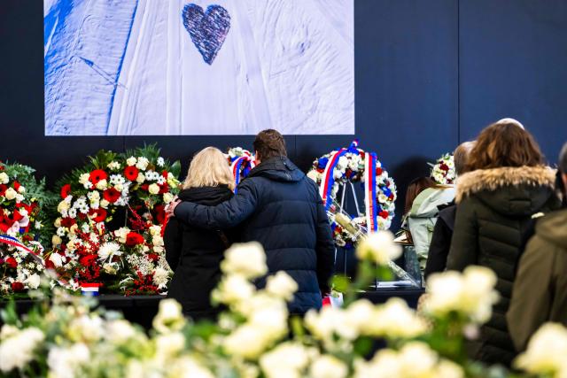 Relatives of victims observe a moment of silence in front of floral wreaths after a tribute ceremony for the victims of the deadly fire that ripped through the bar Le Constellation in Crans-Montana on New Year's Eve, in Martigny, on January 9, 2026. All of Switzerland will mark a national day of mourning on January 9 for the dozens of mostly teenagers killed when fire ravaged a ski resort bar crammed with New Year revellers. Just over a week after the tragedy at the Le Constellation bar in Crans-Montana, which left 40 dead and 116 injured, the wealthy Alpine nation will come to a standstill for a minute of silence at 2:00 pm (1300 GMT). (Photo by LAURENT GILLIERON / POOL / AFP)