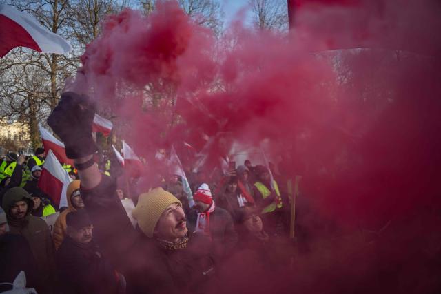 A participant holds up a smoke flare during a protest against the EU-Mercosur agreement in Warsaw, Poland on January 9, 2026. The EU gave on January 9, 2025 a long-delayed go, ahead to a huge trade deal with South American bloc Mercosur championed by business groups but loathed by many European farmers. (Photo by Wojtek RADWANSKI / AFP)
