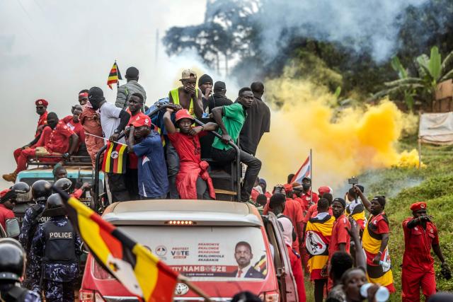 Supporters of opposition leader and presidential candidate for the National Unity Platform (NUP) Robert Kyagulanyi Ssentamu, popularly known as Bobi Wine, gather stranded on a road amid clouds of tear gas fired by Ugandan police as they follow his convoy on the way to a campaign rally in Mukono on January 9, 2026, ahead of the 2026 Ugandan general elections. (Photo by Luis TATO / AFP)